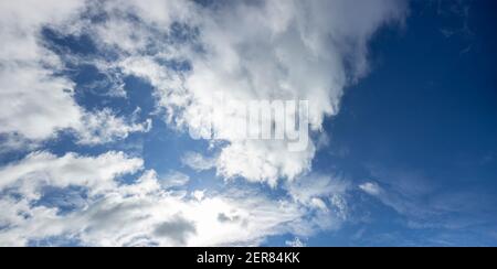 White clouds in the blue sky and bright sun behind the clouds. Stock Photo