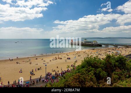 View of the Bournemouth beach and pier as well as scenic calm Atlantic ocean and blue sky. Aerial, bird eye view taken from the east cliffs with green Stock Photo