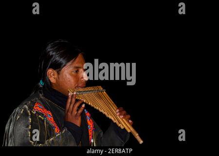 Nazare, Portugal, 07-11-2010: A native south American street performer wearing traditional clothes is playing bamboo panflute , a prominent Andean mus Stock Photo