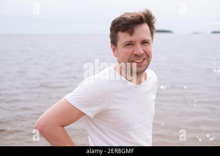 Middle aged caucasian man standing at the beach smiling. Stock Photo