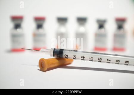 Uncovered syringe and vaccine ampules or glass vials. Selective focus. Isolated over white Stock Photo