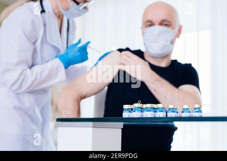 Doctor vaccinates a patient. Coronavirus Covid-19 vaccine ampoules. Stock Photo
