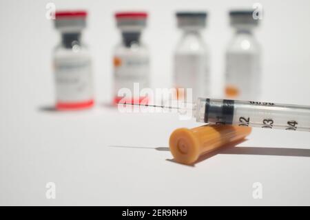 Uncovered syringe and vaccine ampules or glass vials. Selective focus. Isolated over white Stock Photo