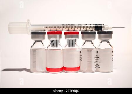 Uncovered syringe and vaccine ampules or glass vials. Selective focus. Isolated over white Stock Photo