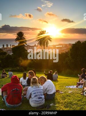 Tourists and Hawaiian people gathered to watch sunset from lookout at Mount Tantalus in Puu Ualakaa State Park, Oahu, Honolulu, Hawaii, USA Stock Photo