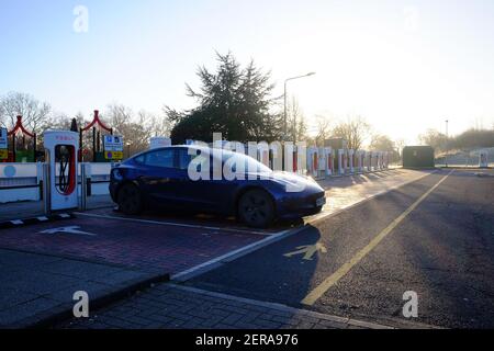 February 2021 - Tesla Model 3 on charge at Tesla super chargers in UK motorway services, Hopwood park, morning rush hour on a working day in lockdown Stock Photo