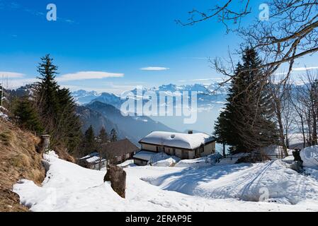 Unique panoramic alpine skyline view of Rigi resort. Snowed Chalets, wooden lodging cabins, hotels, iced Swiss Alps, blue sky. Mount Rigi, Weggis, Luc Stock Photo
