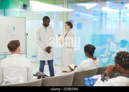 Portrait of young woman standing by whiteboard while giving presentation during medical seminar in college, copy space Stock Photo