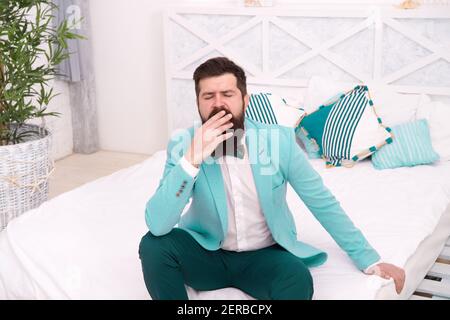 Tired of waiting. Elegant man yawn sitting on bed. Bearded man in classy style. Fashion look of groom. Wedding man. Formal wear for gentleman. Fashion and style. Best man. Stock Photo