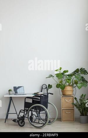 Vertical background image of empty armchair by home office workplace in minimal interior against white wall, copy space Stock Photo