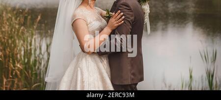 The bride put her hand on the groom's shoulder in a brown suit outdoor. Stock Photo