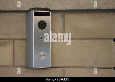 Silver intercom panel with video camera, on a brick beige fence pillar of a private house Stock Photo