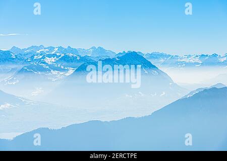 Unique panoramic alpine skyline aerial landscape view of misty iced Swiss Alps peaks in blue sky. Mount Rigi Switzerland in spring. Travel concept.