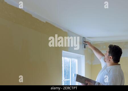 Professional construction worker applying plaster coating to the freshly plasterboard wall during room renovation Stock Photo