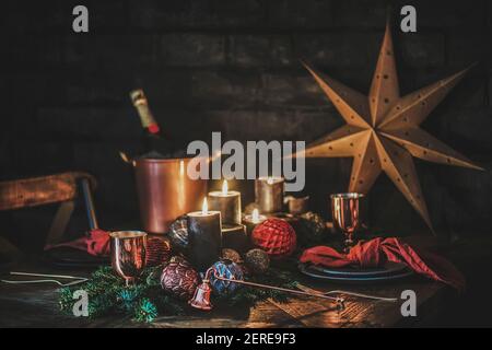 Christmas holiday festive table setting. Dinnerware, cutlery, champagne, golden star on wood table decorated with fur tree branches, candles, black br Stock Photo
