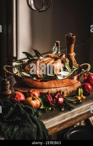 Whole roasted chicken for winter holiday festive dinner in copper roasting tin with spices, herbs and fruit on kitchen counter. Christmas or Thanksgiv Stock Photo