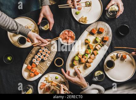 Family lockdown Japanese food sushi dinner from delivery service at home. Flat-lay of table with various salmon, crab, prawn and vegan rolls, wasabi a Stock Photo