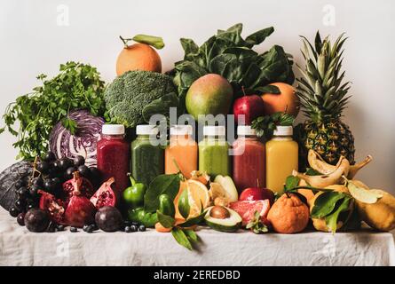 Various fresh smoothies for detox weight loss diet program. Colorful juices in vacuum bottles with fruit, vegetables and greens ingredients on table. Stock Photo