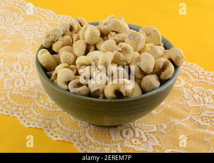 Brazilian sweet kettle corn popcorn in ceramic snack bowl on white lace table runner on yellow tablecloth Stock Photo
