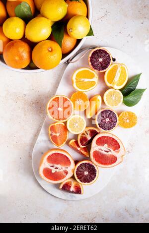 Flat lay citrus fruits with cut up lemons, grapefruits, oranges, blood oranges, and lemons on a cutting board. Stock Photo