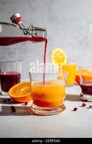 Fresh squeezed pomegranate juice being poured into orange juice Stock Photo