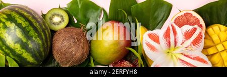 Creative flat lay with tropical fruits and plants on pink background Stock Photo