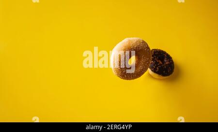 Various decorated doughnuts in motion falling on yelloy background. Sweet and colourful doughnuts falling or flying in motion. Stock Photo