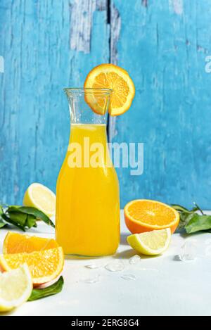 Bottle of orange juice and fresh fruits on light blue wooden table ...