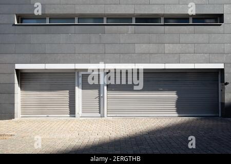 Front view metal roller shutter doors and metal door at service area back of office building. Stock Photo