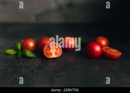 Red cherry tomatoes with green basil on a gray background. High quality photo Stock Photo