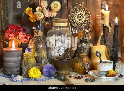 Still life with potion and elixir bottles, burning candles and magic ritual objects on witch table. Esoteric, gothic and occult background, Halloween Stock Photo