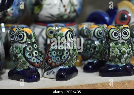 A man is seen painting pottery dishes in a small factory located in