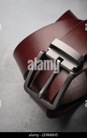 Brown leather belt with accent belt buckle on grey background. Stock Photo