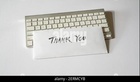 Thank you letter on top of keyboard. Isolated, white background. Stock Photo