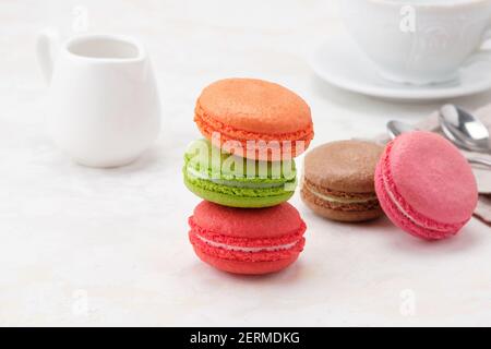 Beatiful colorful Macaroons on a white background. On background with white milkman and a white cup of tea or coffee  Stock Photo