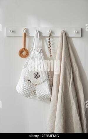 White string bag with toilet paper weighs on white wall. Reusable eco-friendly products. Zero waste and sustainable plastic free lifestyle.  Stock Photo