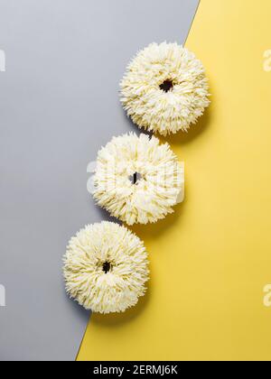 Shag donuts on two color gray and yellow background. Unusual trendy donuts with white vanilla buttercream. Copy space. Top view or flat lay. Vertical Stock Photo