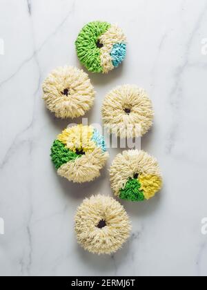 Shag donuts on white marble background. Unusual trendy colorful donuts with vanilla buttercream. Copy space. Top view or flat lay. Vertical Stock Photo