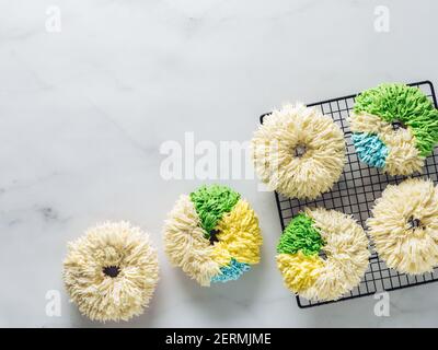 Shag donuts on white marble background. Unusual trendy colorful donuts with vanilla buttercream. Copy space. Top view or flat lay. Stock Photo
