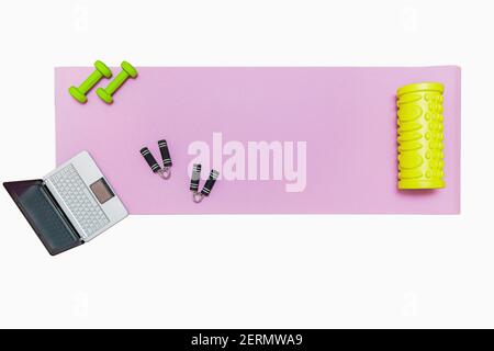 Fitness mat, dumbbells, expander and laptop for online workouts at home. Online education concept in relation to the pandemic. Isolated on white Stock Photo
