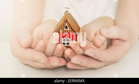 real estate and family home concept - closeup picture of child and female hands holding red paper house with family. High quality photo Stock Photo