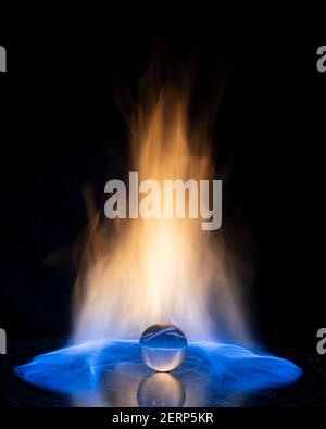 Glass ball with fire flames on black background. Copy space. Stock Photo