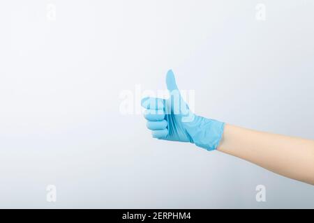 Hand of surgeon in blue medical glove showing a thumb up Stock Photo