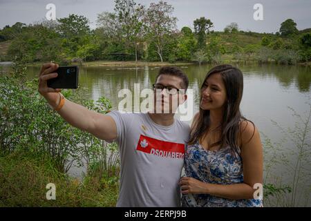 Puerto Triunfo, Colombia. 18th Feb, 2021. Ignacio Mazo and María Palacio pose for a selfie while watching hippos at the 'Hacienda Nápoles' theme park. The hippos, once brought to Colombia by drug lord Pablo Escobar, have multiplied so much that the country is looking for a solution for the animals. Credit: Luis Bernardo Cano/dpa/Alamy Live News Stock Photo