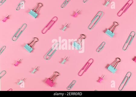 Stationery items like paper clips and drawing pins arranged on pink background Stock Photo