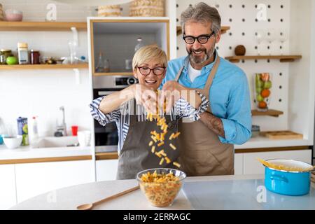 Senior couple having fun, cooking in home kitchen Stock Photo