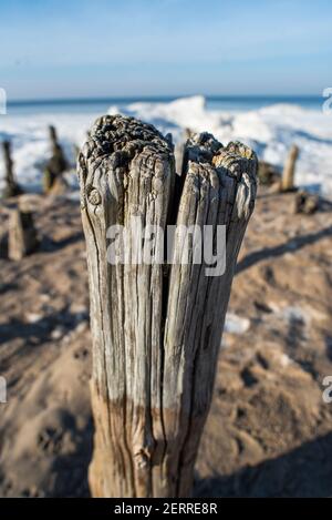 Pile stuck in the sand on the beach, the debris of the pier. Stock Photo