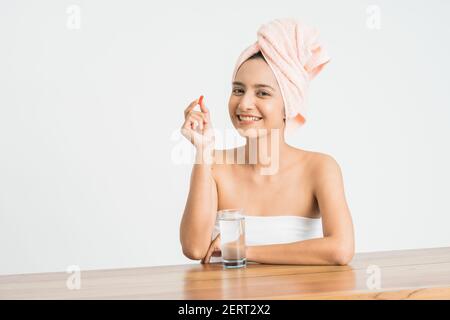 Young asian beauty young woman eating pills and drinking water on white background. Stock Photo