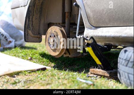 own repair of car drum brake himself. repair of broken car drum brake disassembled outdoor Stock Photo