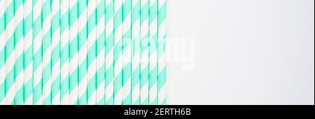 pile of paper striped white and green drinking straws for party on white background. banner Stock Photo